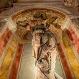 La scultura, ricavata da un unico blocco di pietra policroma locale, raffigura il santo in abiti da guerriero con scudo e spada sguainata mentre tiene alla catena un drago, simbolo del diavolo